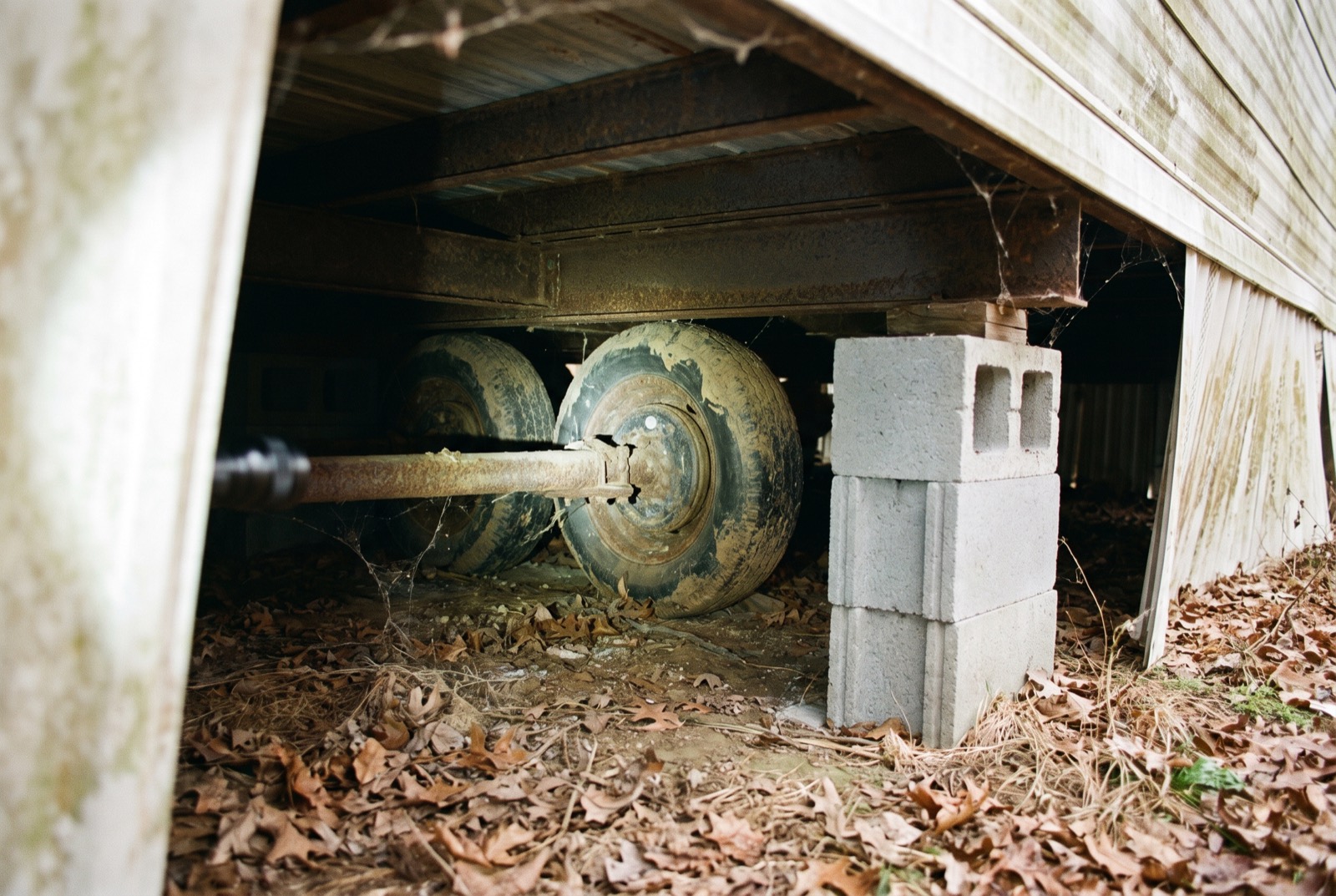 An old axle and tires still under a manufactured home beside a newer block pier